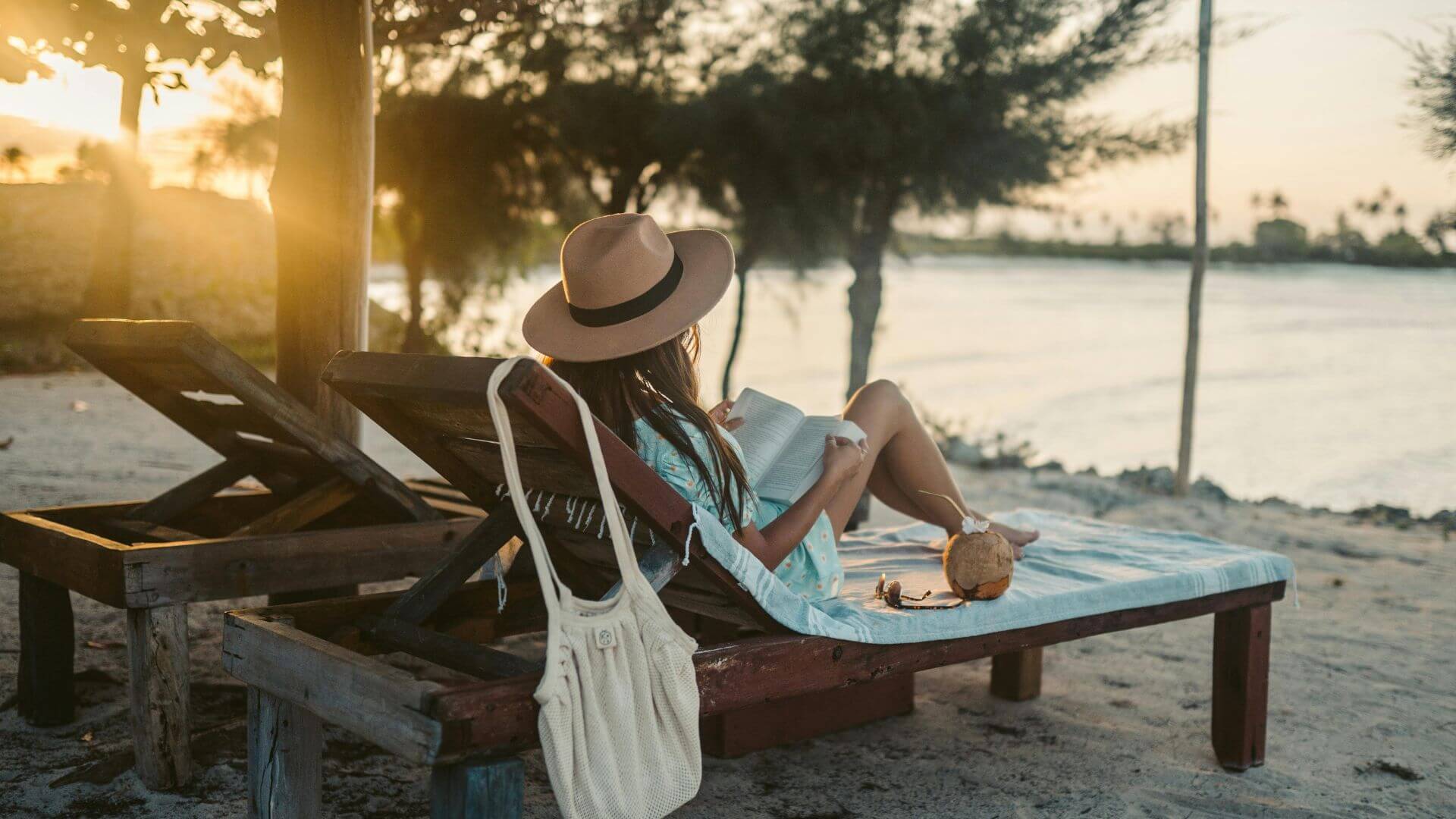 woman is reading a book on the beach
