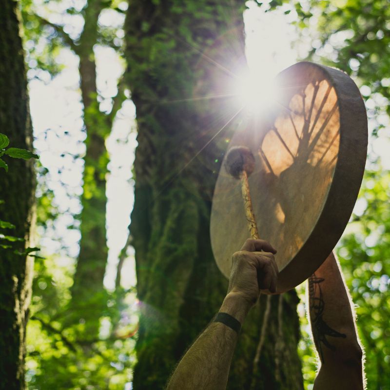 playing a shamanic drum in the forest