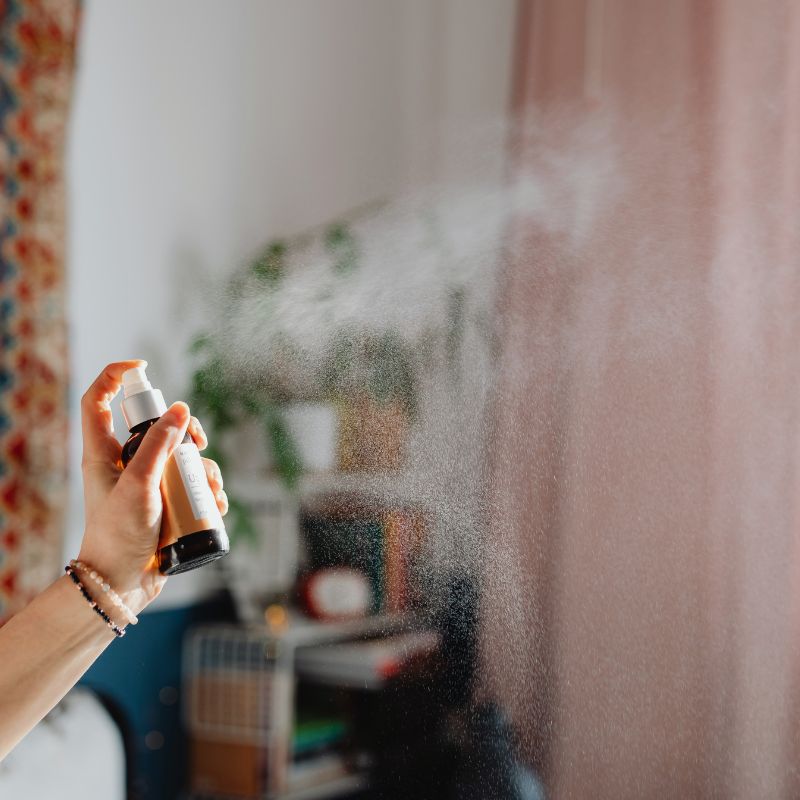 a woman is using a room spray